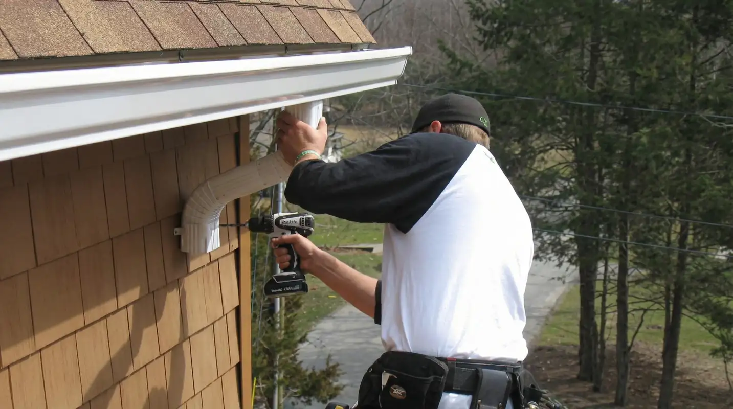 Professional contractor installing tan vinyl siding panels on a residential home exterior in Syracuse, NY